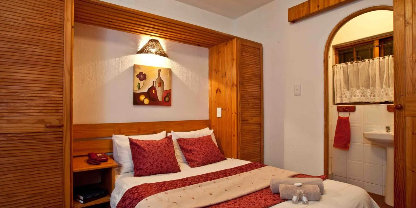 Cozy bedroom with a double bed wooden wardrobe and adjacent bathroom