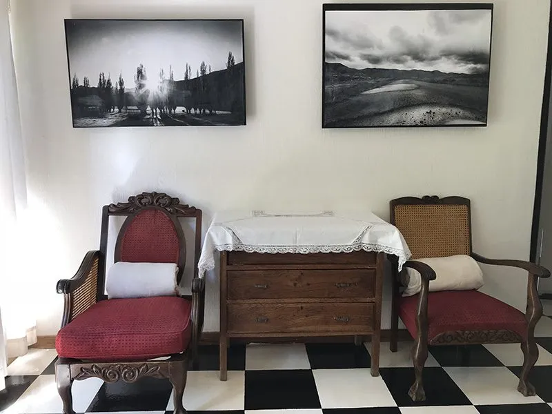 Two red armchairs wooden dresser and black and white artwork on white wall