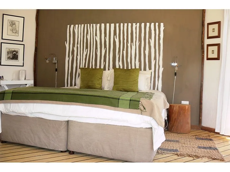 Modern bedroom with unique headboard green pillows and wooden side table