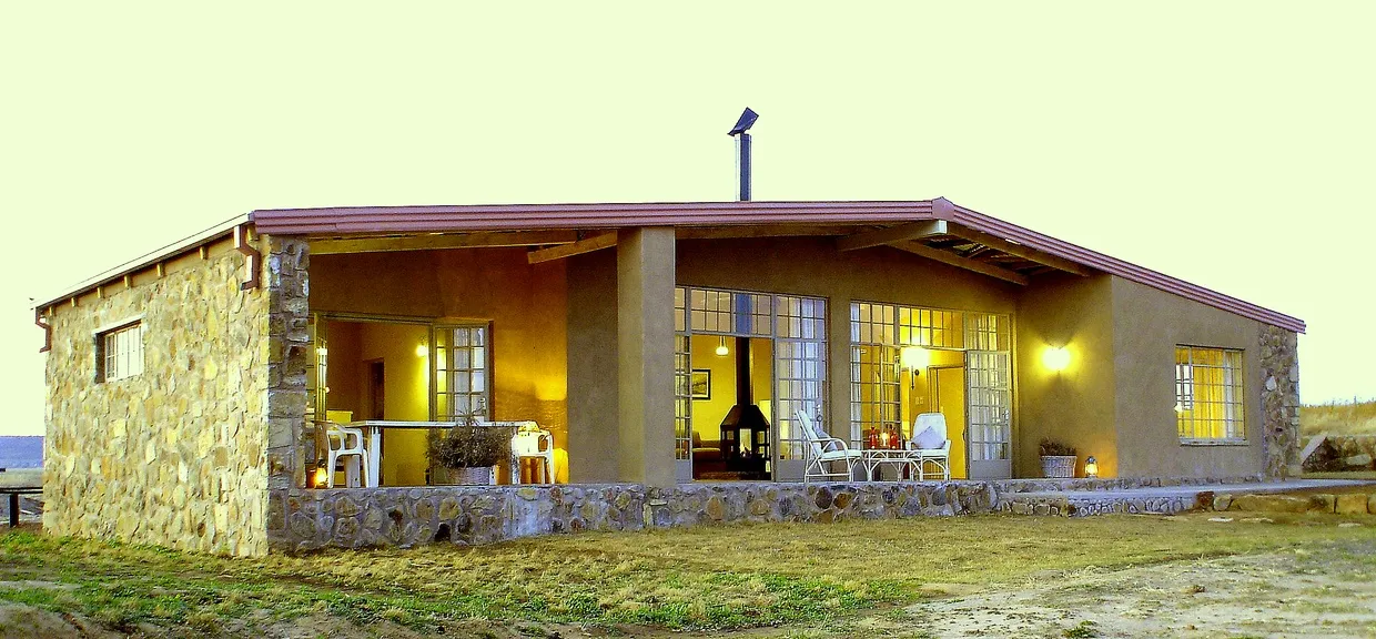 Stone and stucco house with large windows and outdoor seating area
