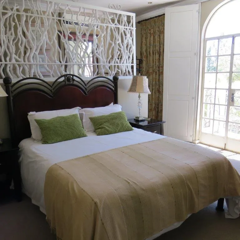 Cozy bedroom with a large bed green pillows and arched window with curtains