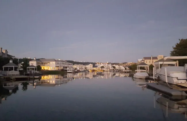 Houses and boats along a calm waterfront at dusk