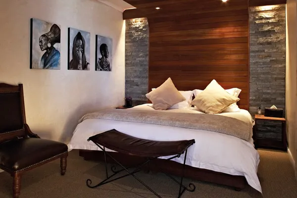 Cozy bedroom with wooden headboard white bed and three portraits on the wall