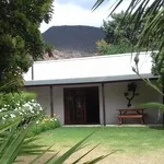 House with a mountain view surrounded by greenery and a wooden bench
