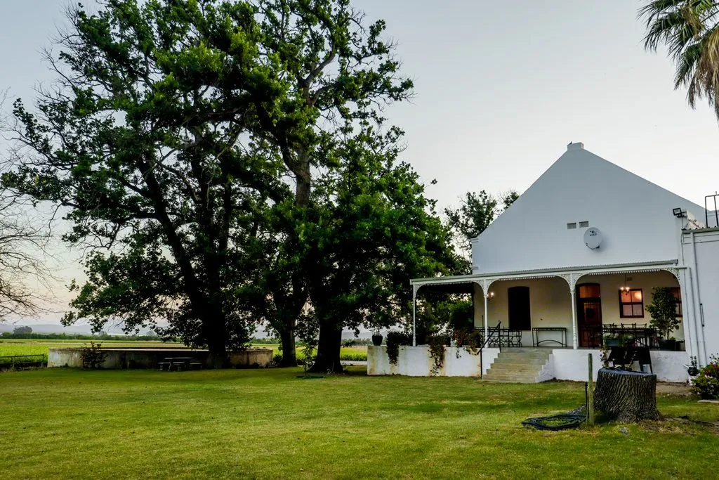 White house with large trees and green lawn in a rural setting