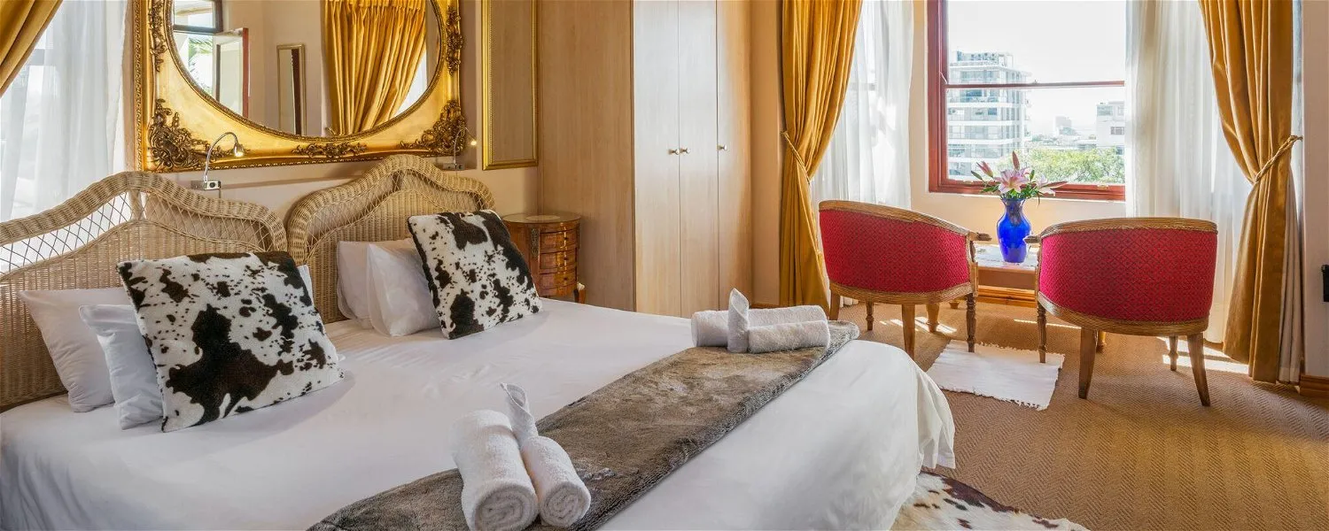 Bedroom with a large bed two red chairs and a window with curtains