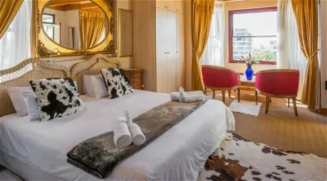 Luxurious bedroom with large bed ornate mirror and red armchairs by window