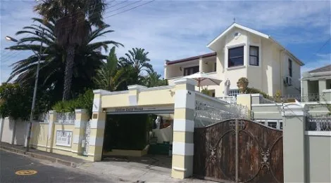 Twostory house with palm trees gated entrance and clear blue sky