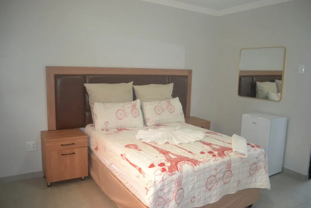 Bedroom with a double bed bedside table mirror and small refrigerator