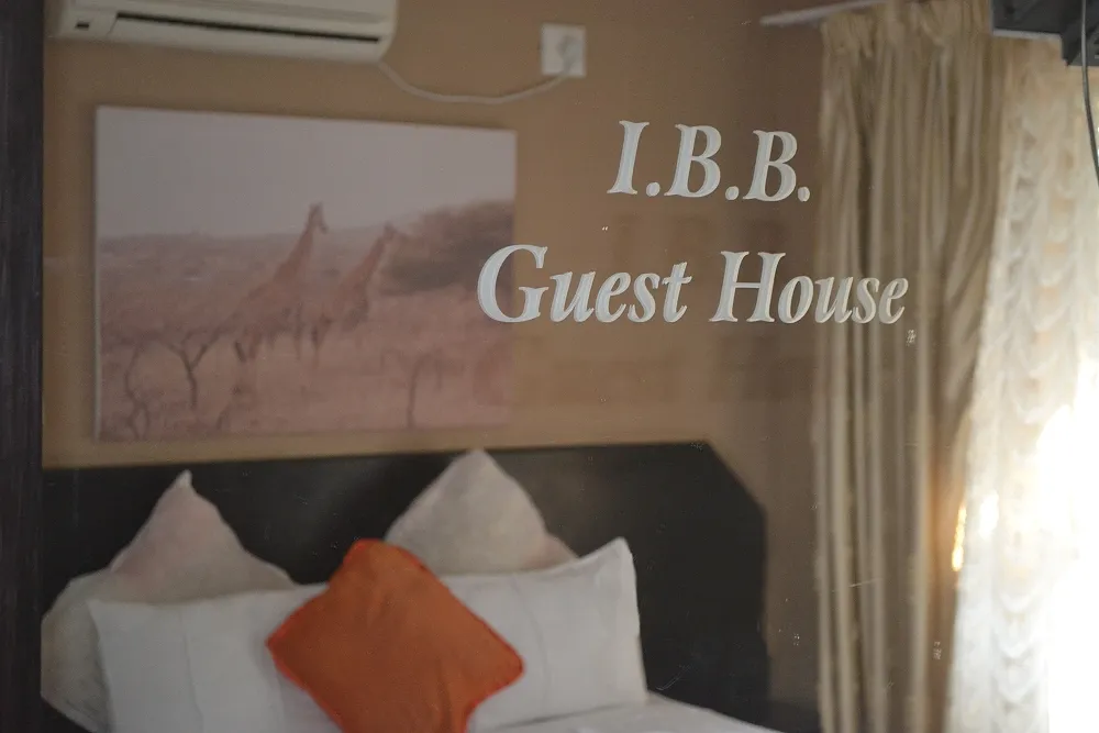 Bedroom with bed pillows and a wall sign reading IBB Guest House