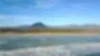Blurry landscape with water mountains and a blue sky