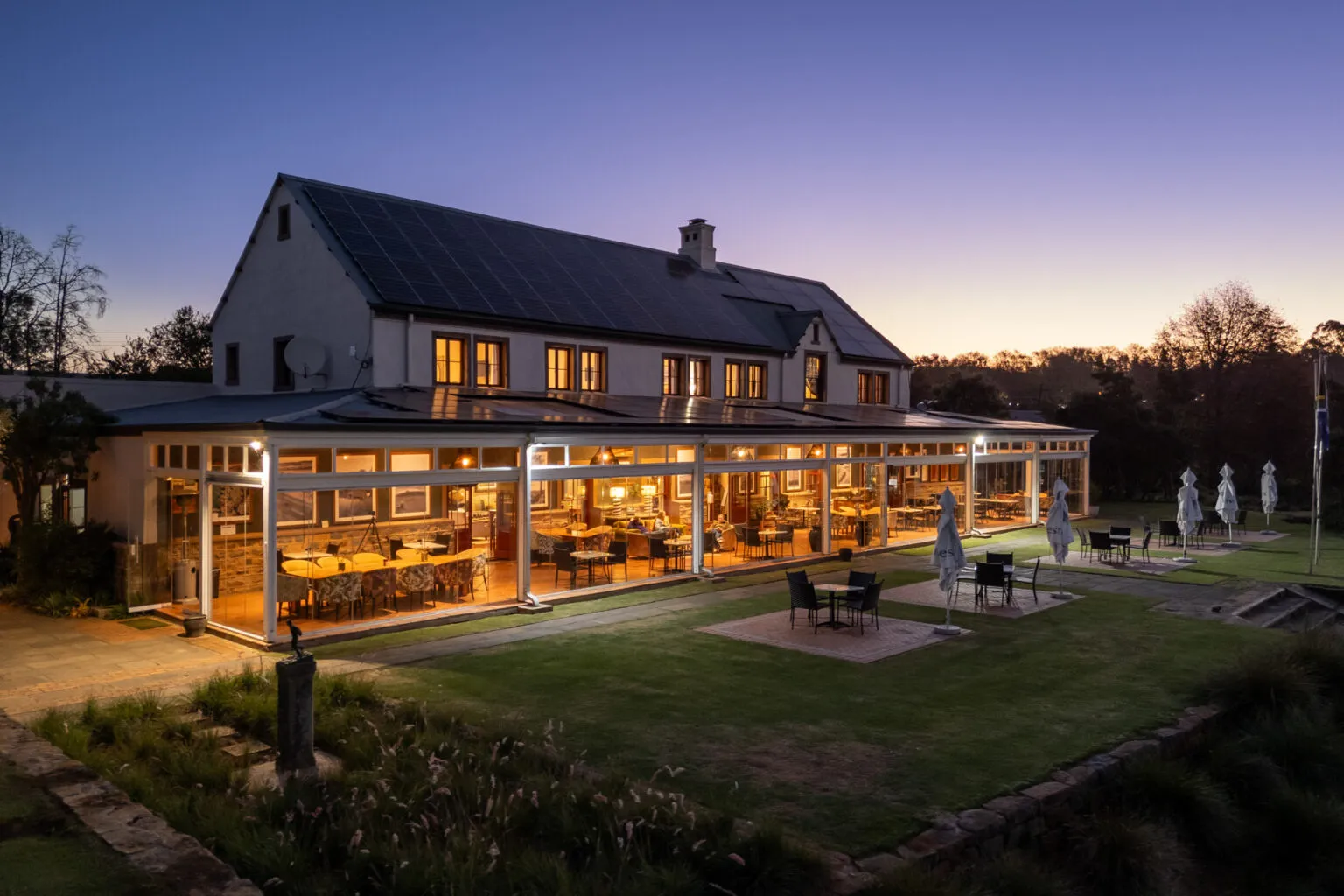 Modern building with large windows and outdoor seating area at dusk