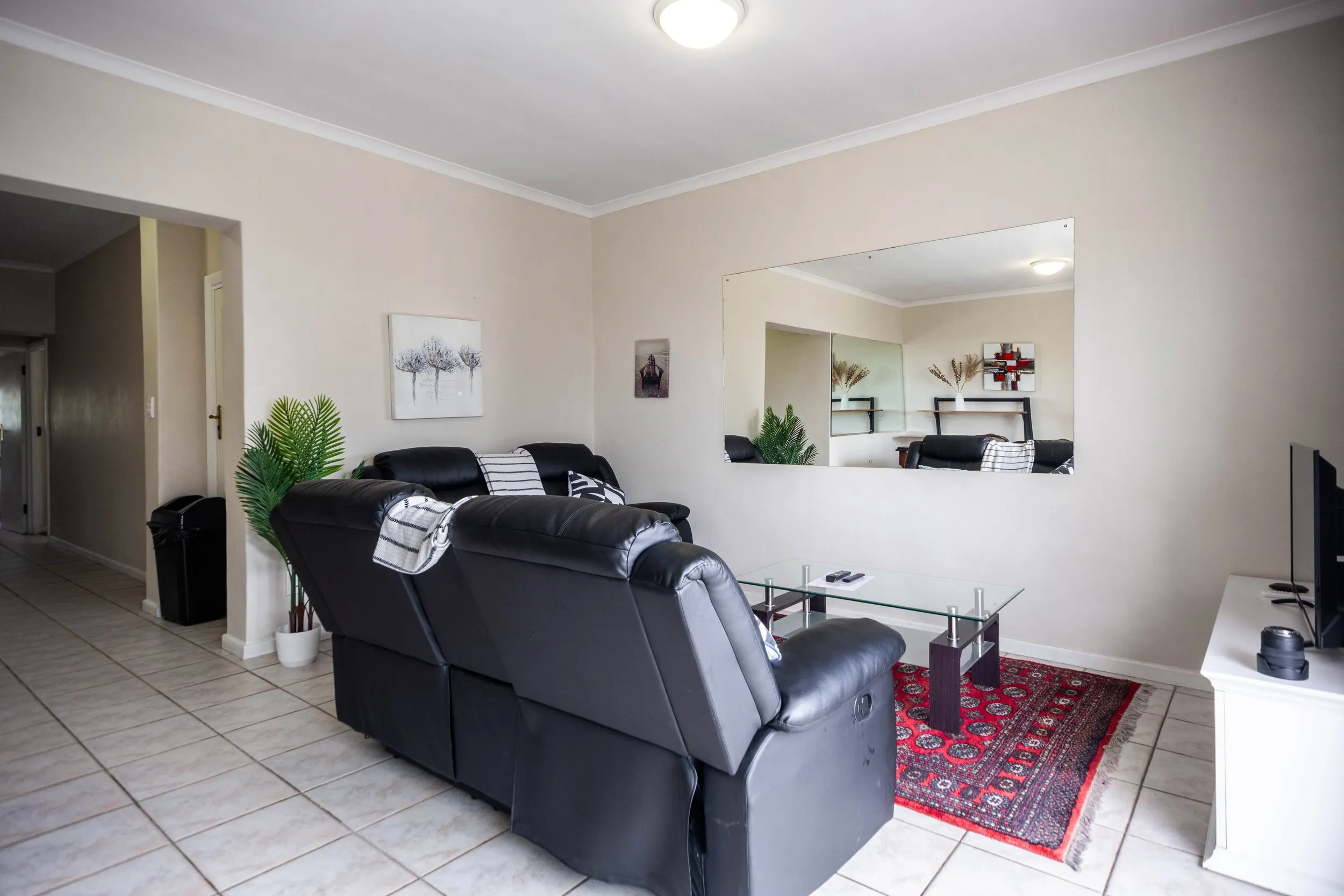Modern living room with black leather recliners glass table and wall mirror