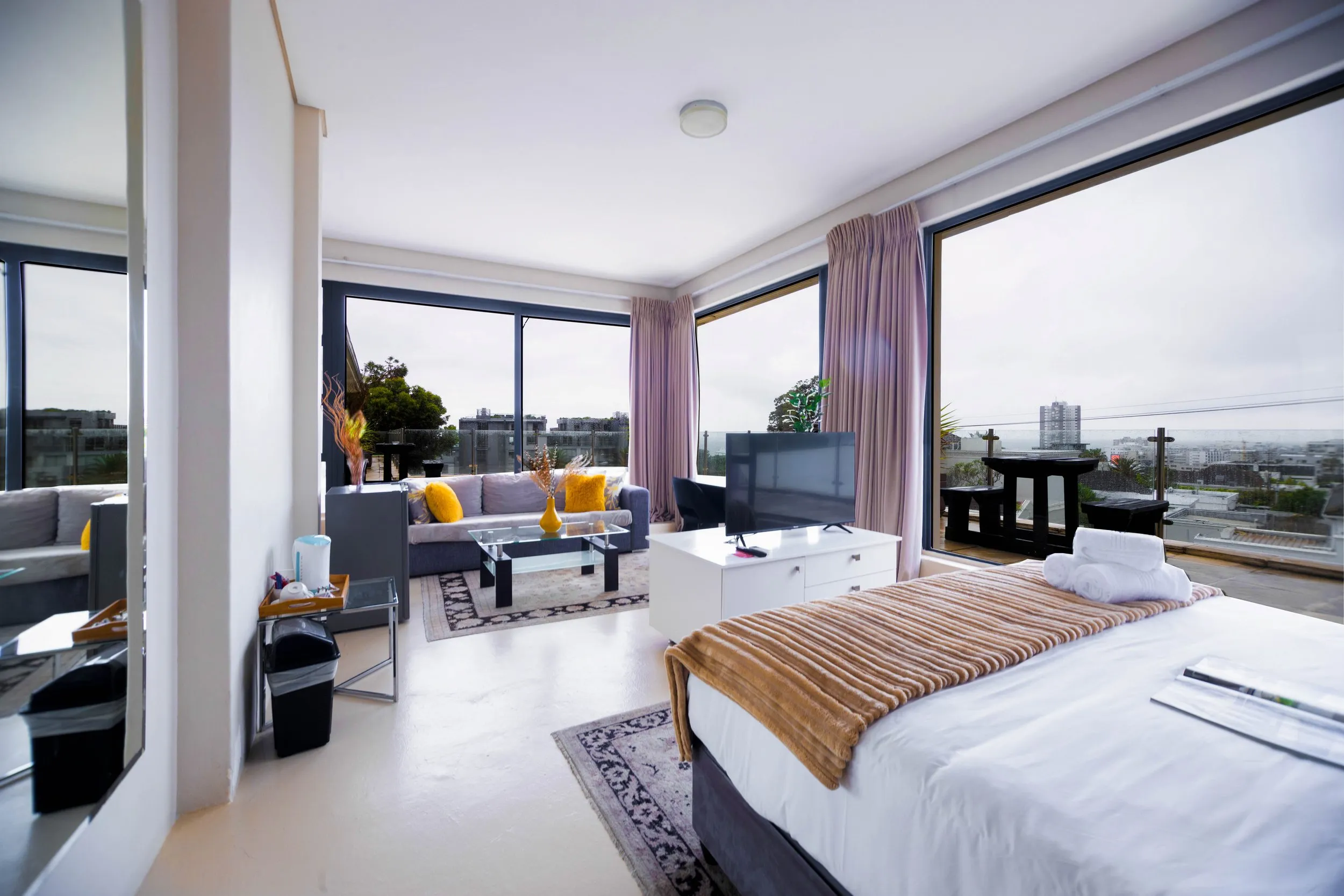 Modern bedroom with large windows city view and adjacent living area