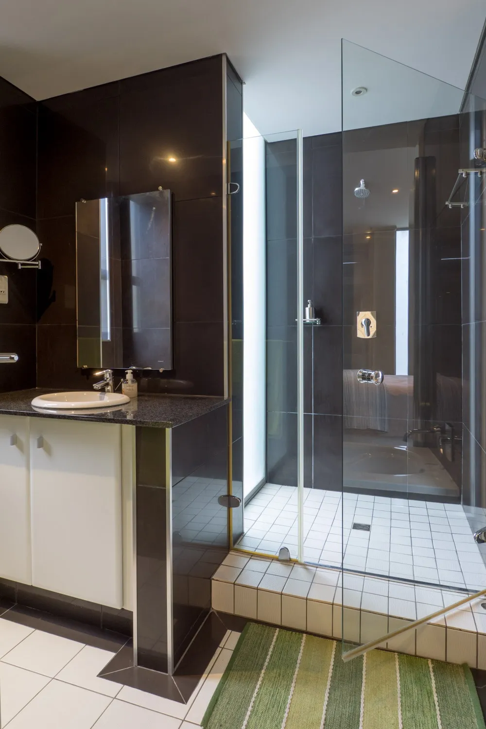Modern bathroom with black tiles white fixtures and glass shower enclosure