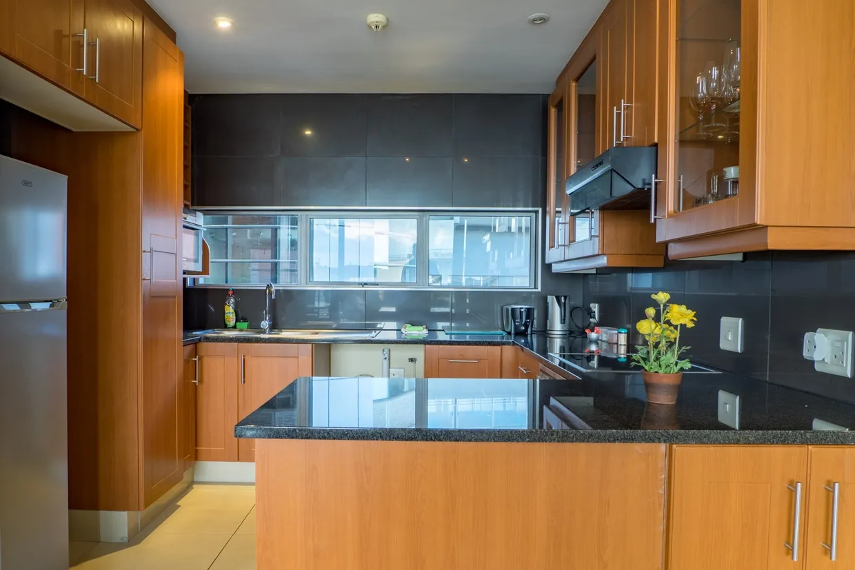 Modern kitchen with black countertops wooden cabinets and large window