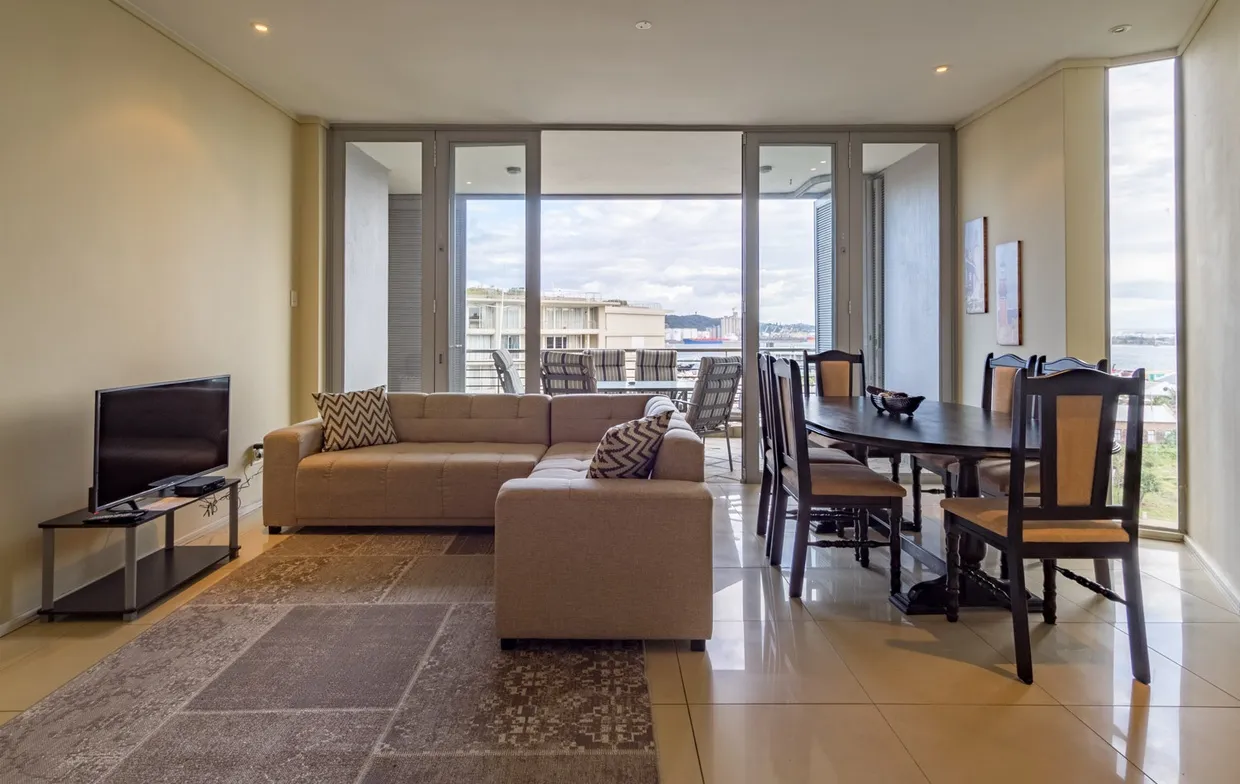 Modern living room with sofa TV dining table and large windows