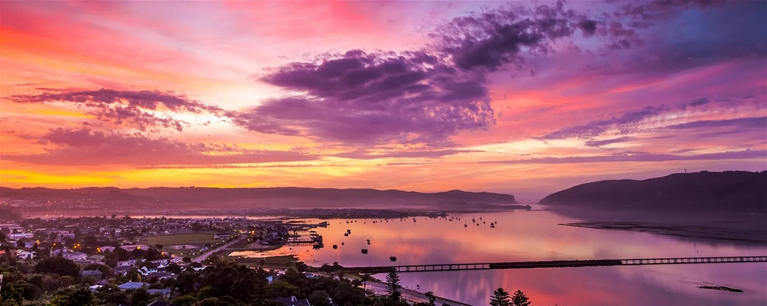 Sunset over a harbor with boats colorful sky and distant hills