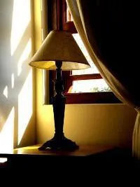 Lamp on a table by a window with sunlight streaming in