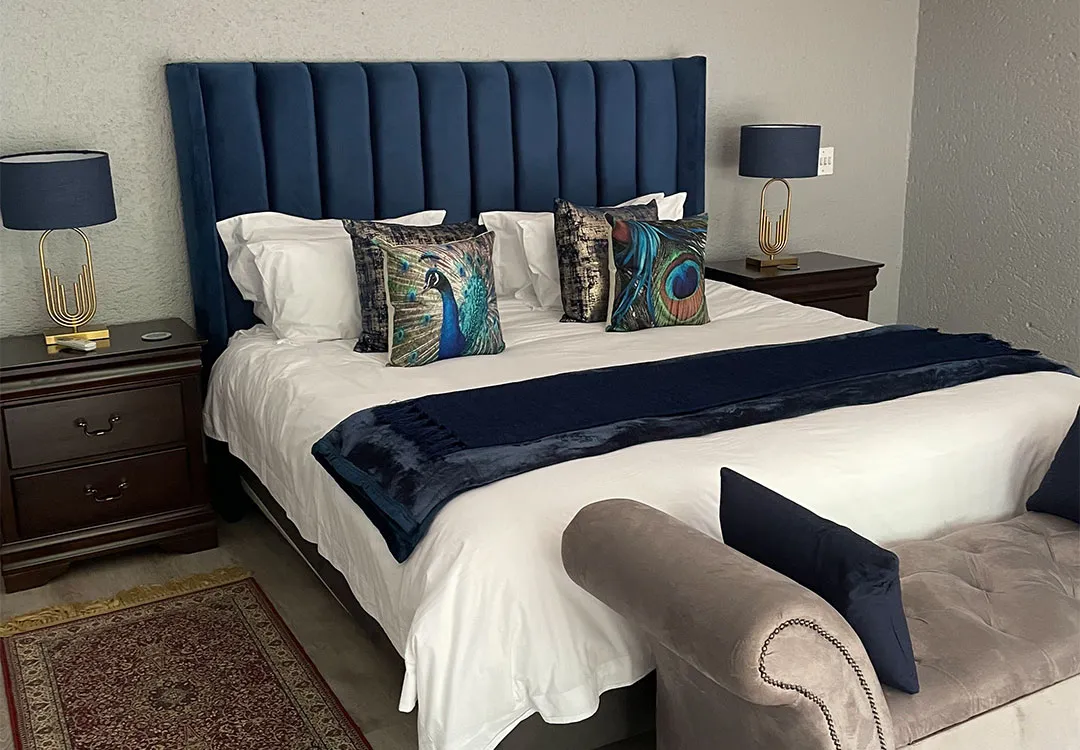 Modern bedroom with a large bed blue headboard and patterned pillows