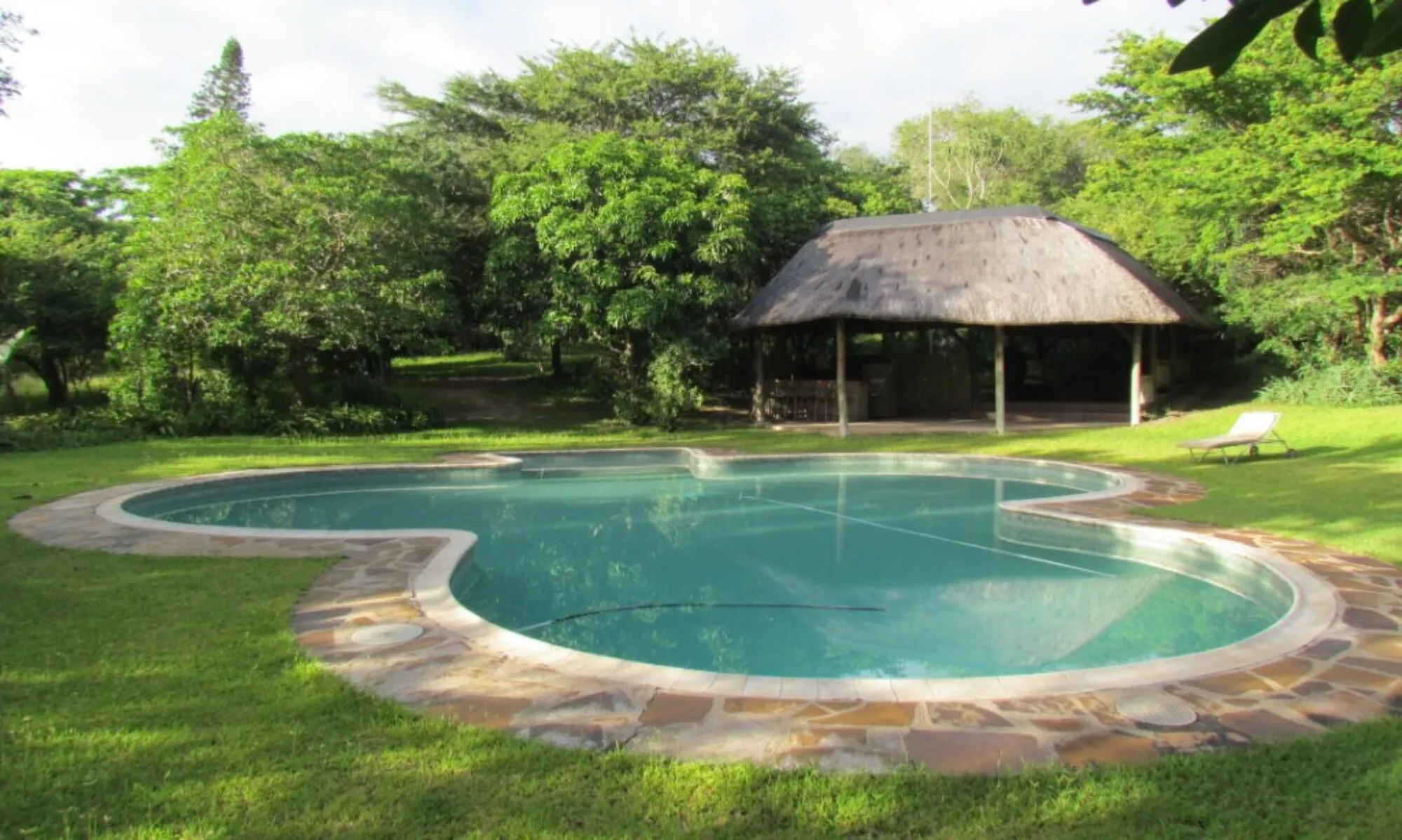 Swimming pool in a lush garden with a gazebo in the background