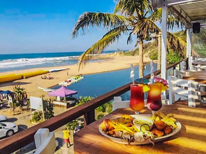 Tropical beach view with food drinks and palm trees on a wooden deck