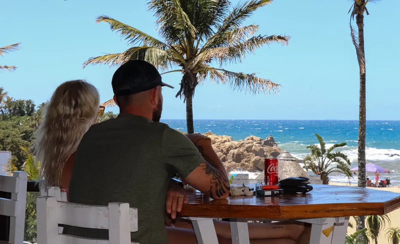 Couple sitting at a beachside table with ocean view and palm trees
