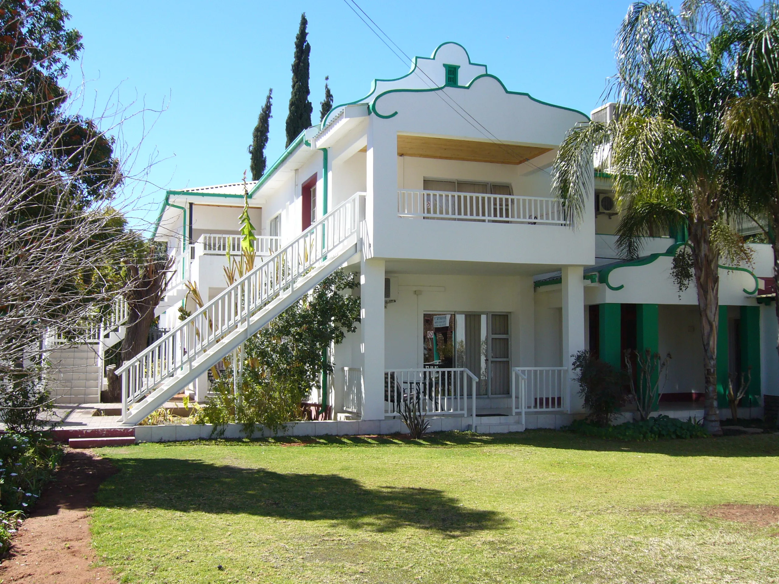 White building with green trim outdoor staircase and surrounding greenery