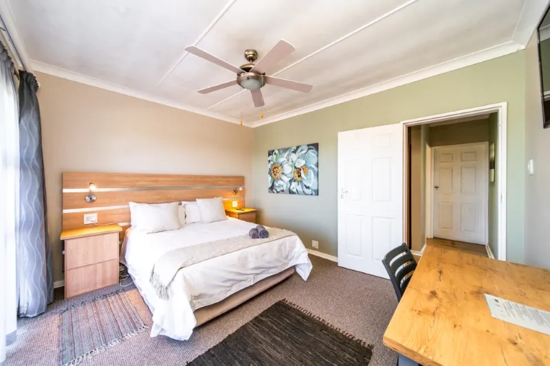 Cozy bedroom with a double bed desk and ceiling fan