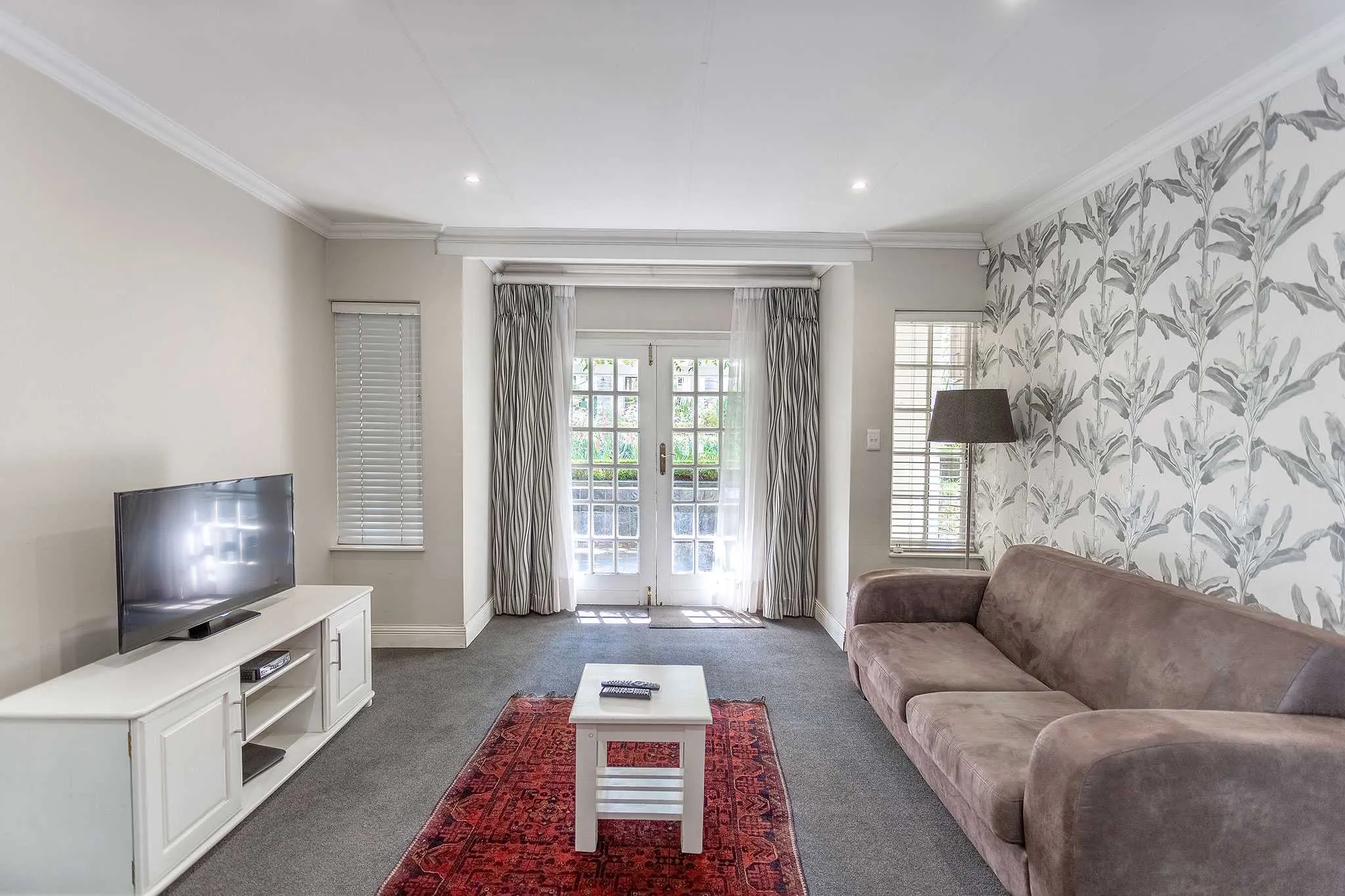 Living room with TV sofa coffee table and French doors to garden