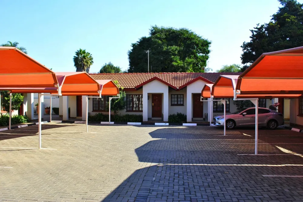 Row of singlestory buildings with red roofs and awnings parked cars