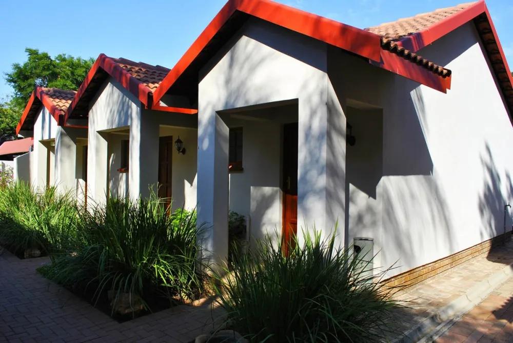 Row of white buildings with red trim and green plants in front