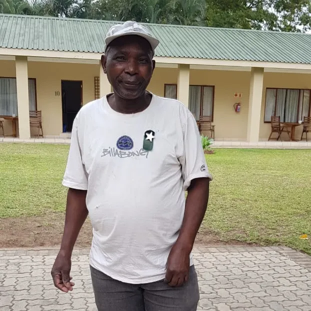 Man in white tshirt standing in front of a greenroofed building