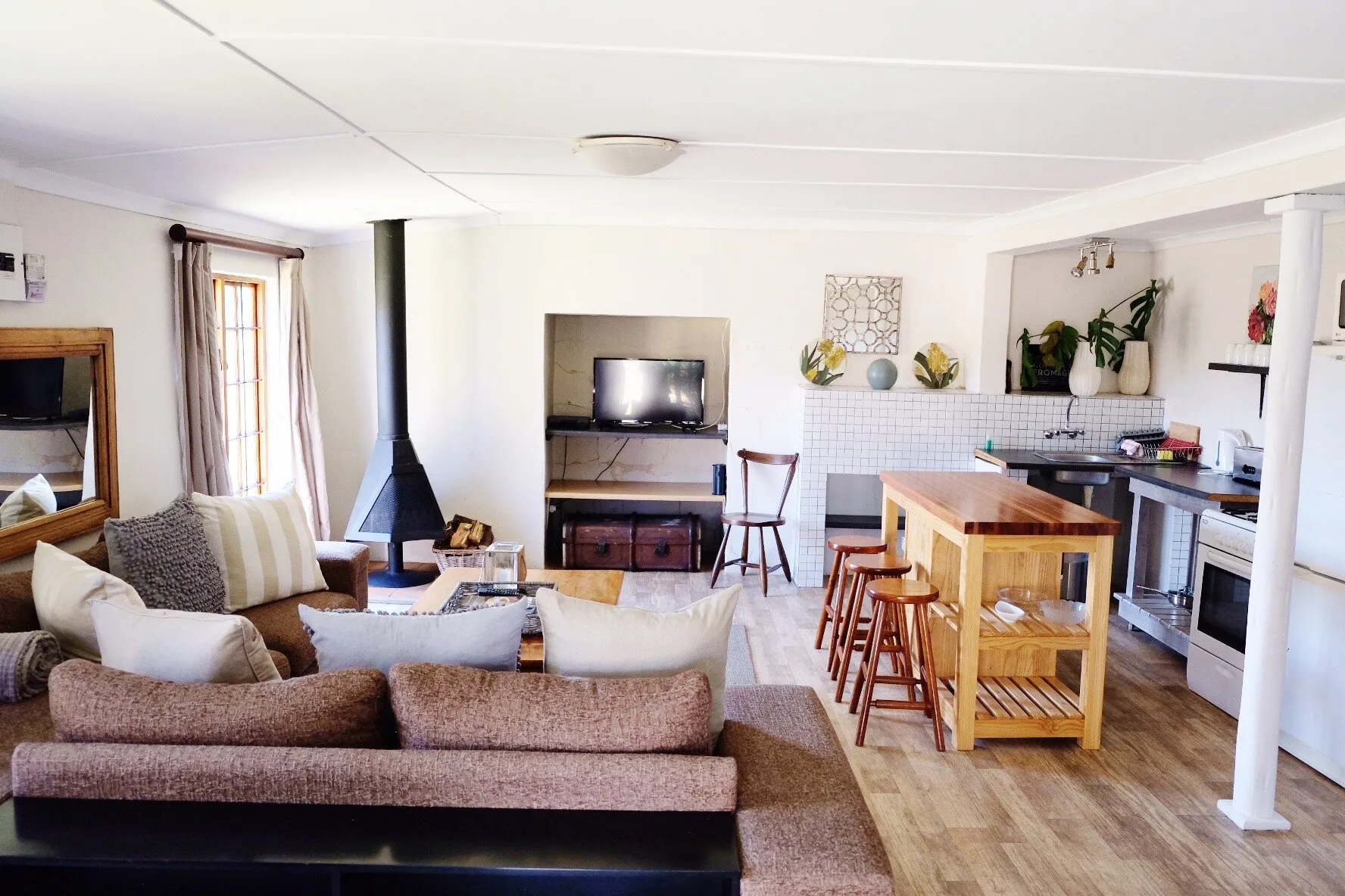 Cozy living room with kitchen area sofa fireplace and wooden stools