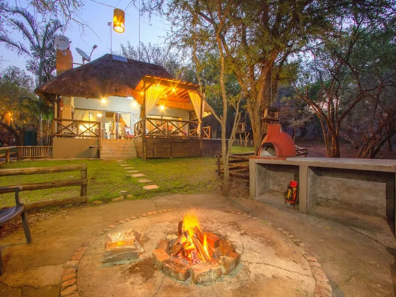 Cozy cabin with outdoor fire pit and pizza oven in a wooded area