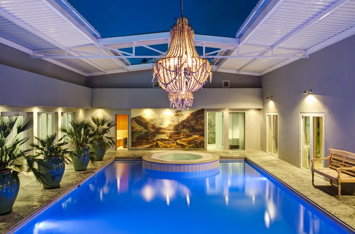 Indoor pool with chandelier plants and mural lit at night