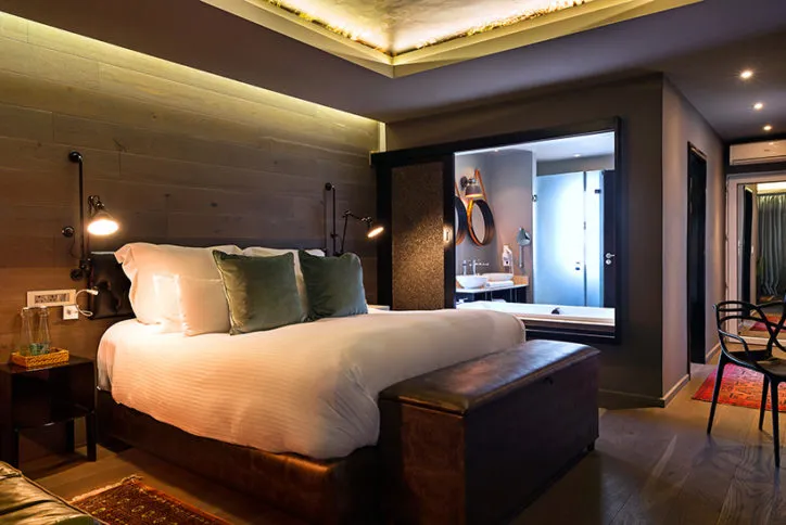 Modern bedroom with a large bed wooden accents and a visible bathroom