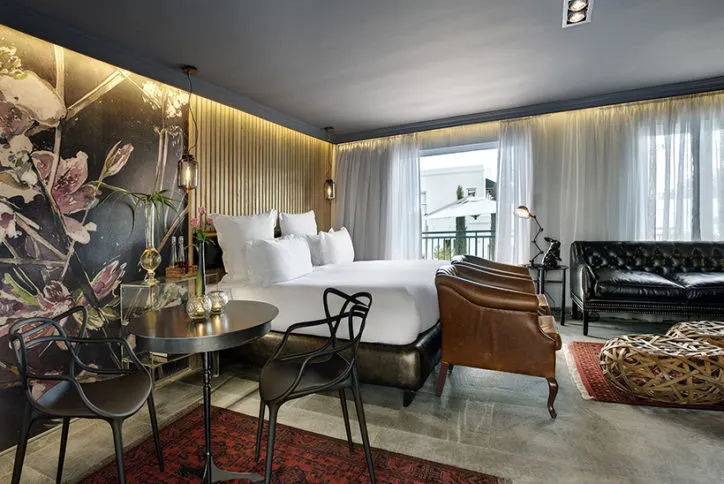 Modern hotel room with bed seating area and floral wall art