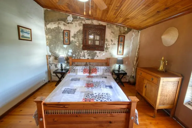 Wooden bed in rustic room with exposed wall and wooden ceiling