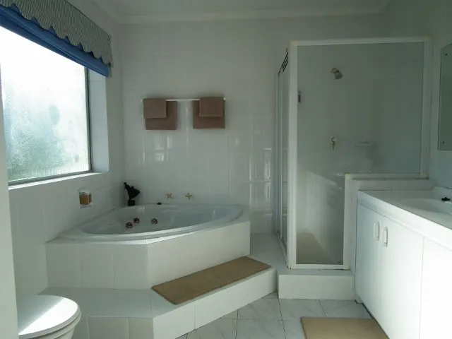 Modern white bathroom with a bathtub shower toilet and frosted window