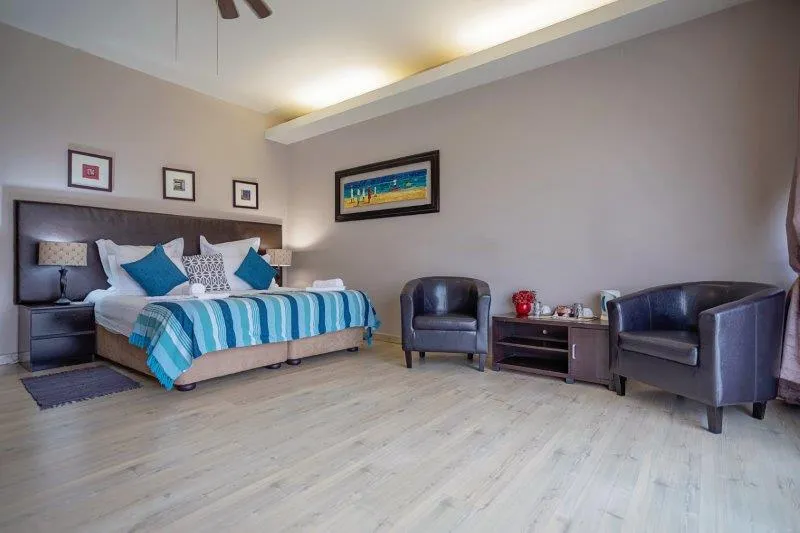 Modern bedroom with a large bed two armchairs and a wooden floor