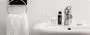 Black and white photo of a bathroom sink with toiletries and towel
