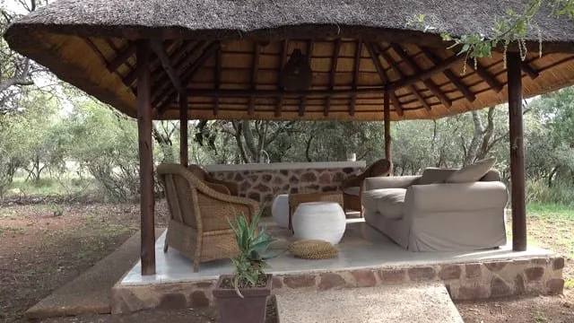 Outdoor seating area with wicker chairs and sofa under a thatched roof