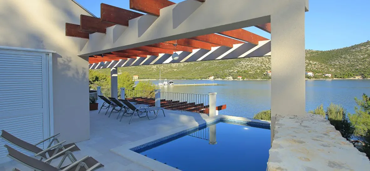 Modern villa with pool overlooking a lake and mountains with lounge chairs