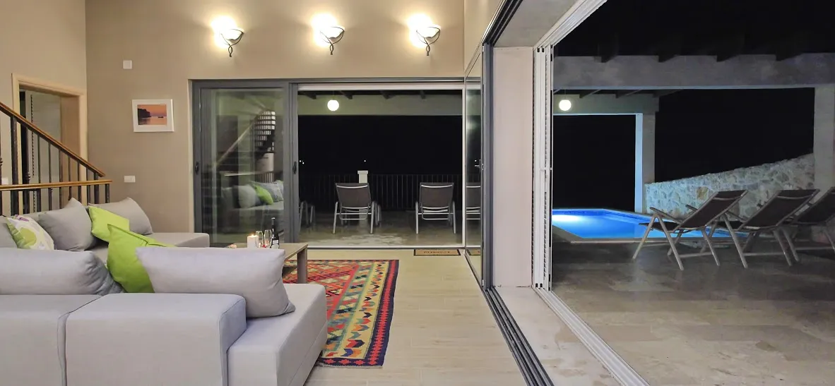 Modern living room with open sliding doors to a pool area at night