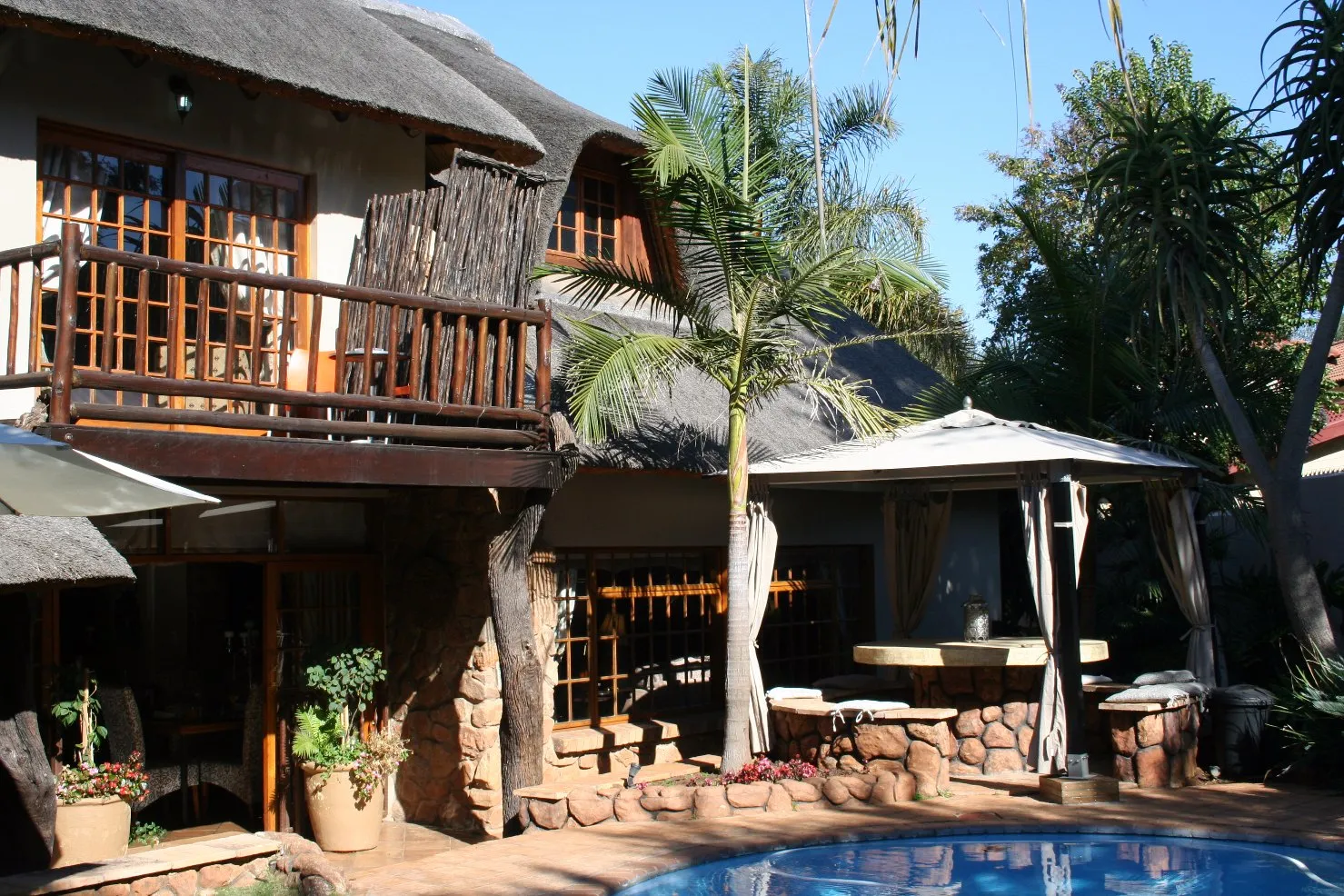 Thatchedroof house with a pool palm trees and outdoor seating area