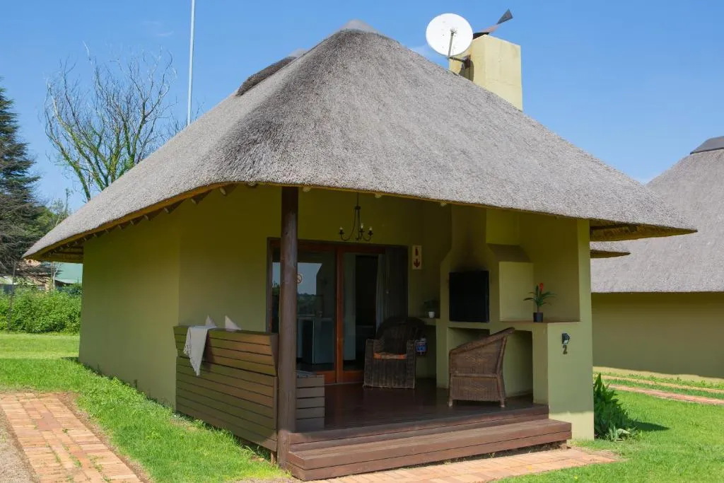 Small thatchedroof cottage with a veranda chairs and a satellite dish