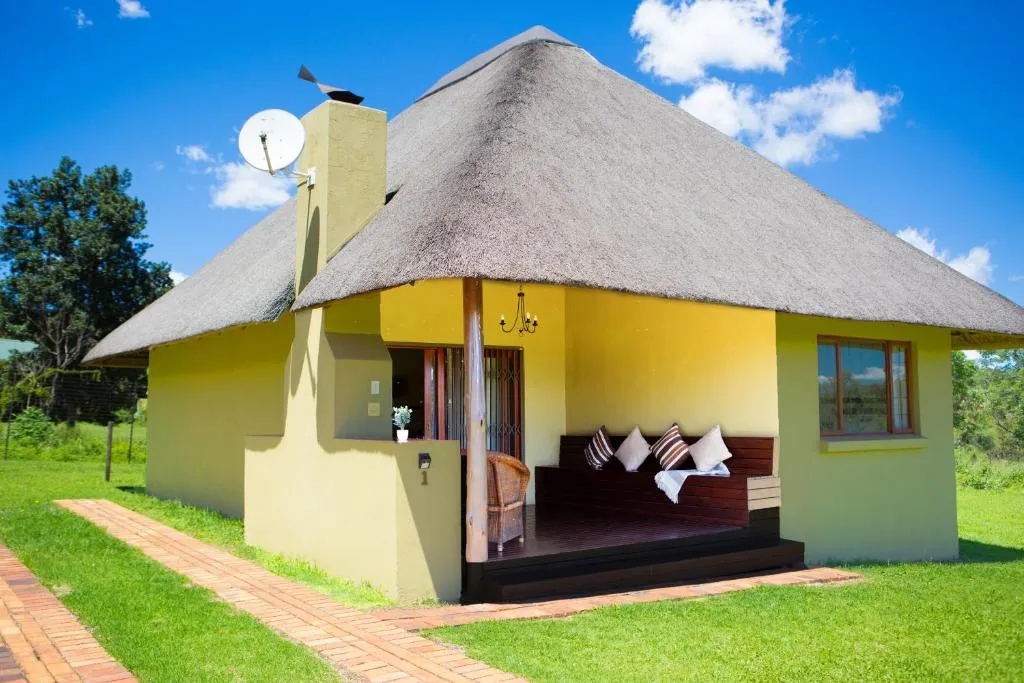 Yellow thatchedroof cottage with a patio set in a green lawn