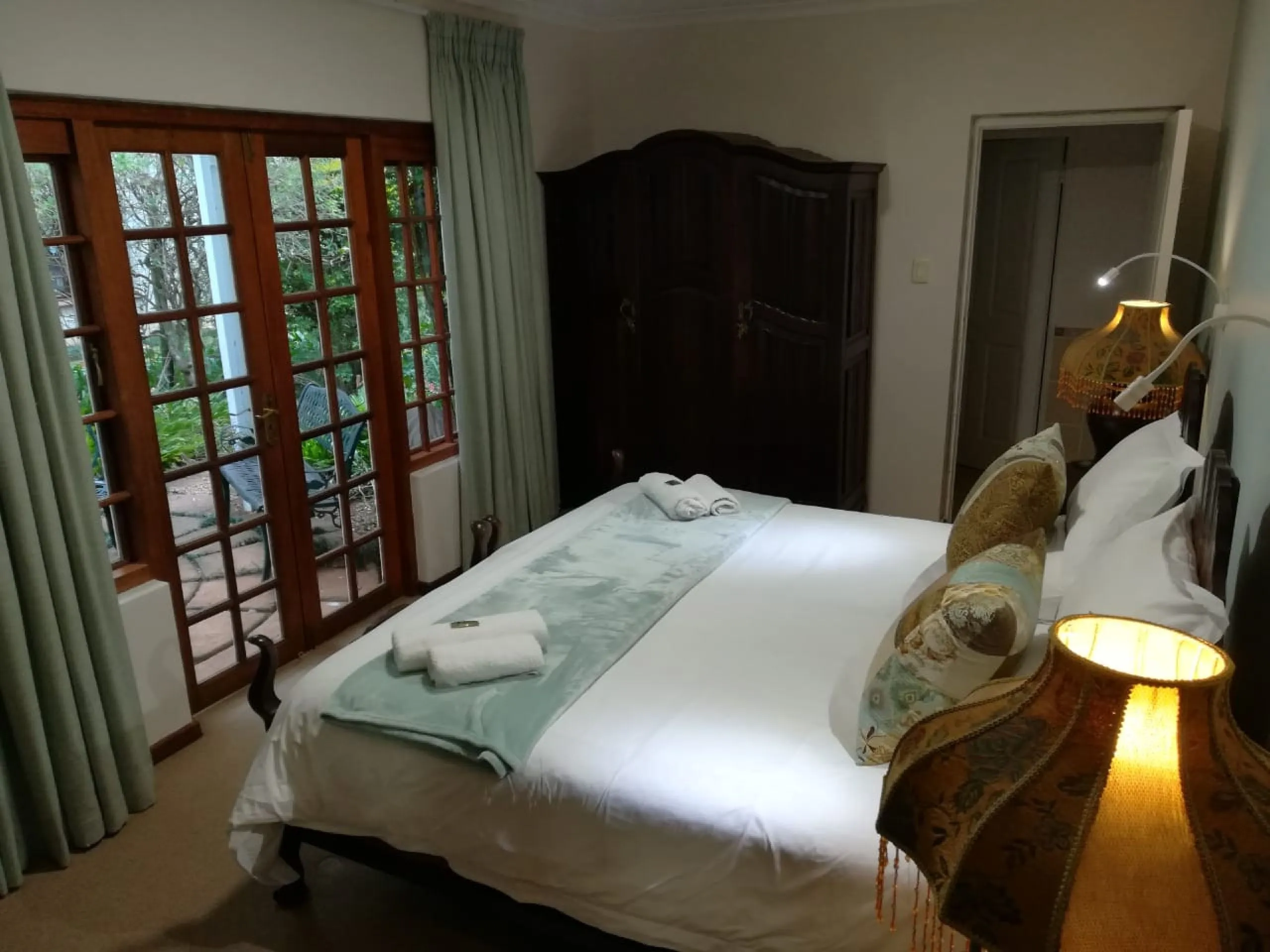 Bedroom with large bed green decor and wooden wardrobe near a window