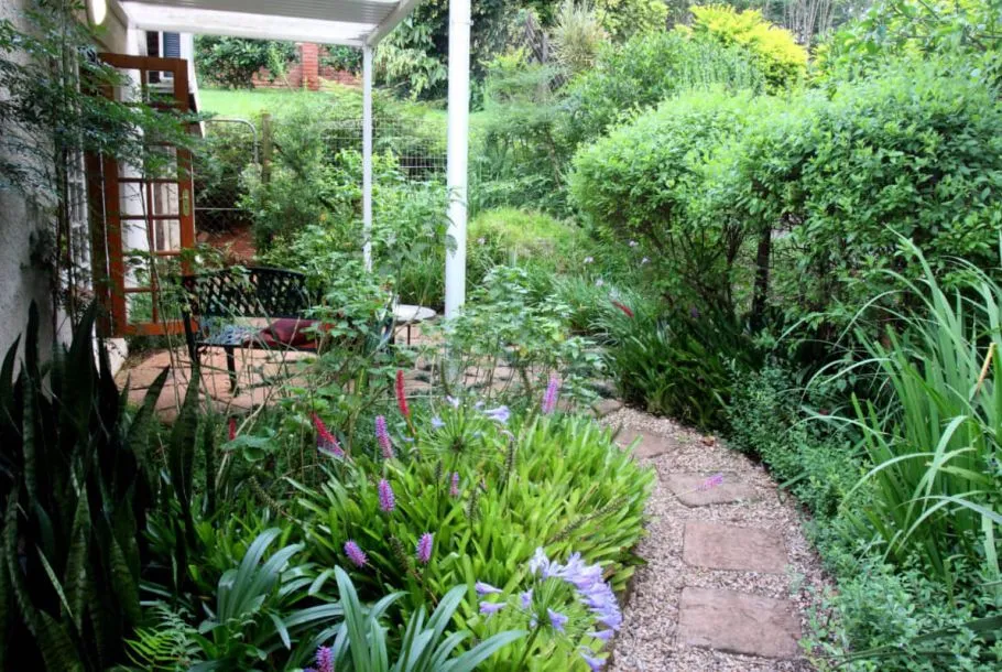 Garden path with purple flowers leading to a patio with a bench